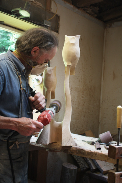 finishing a pair of owls 					carved from red oak